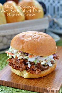 a pulled pork sandwich sitting on top of a wooden cutting board