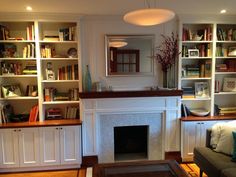 a living room filled with furniture and a fire place in the middle of bookshelves