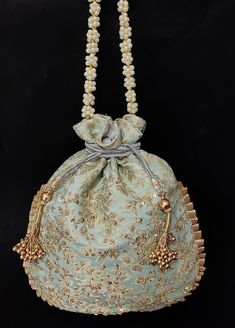 a blue purse with pearls hanging from it's side