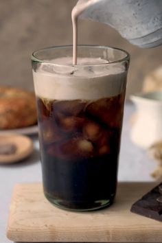 a pitcher pouring liquid into a glass filled with ice