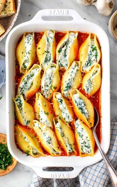 a casserole dish filled with ravioli and spinach, topped with parmesan cheese