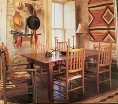 a dining room table and chairs with hats hanging on the wall