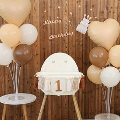 a birthday party with balloons and decorations on the side of a wooden wall behind a baby's cradle