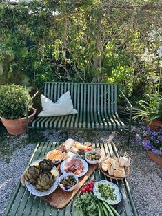 a table with plates of food on it in the middle of a gravel garden area