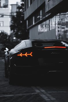 a black sports car parked in front of a building with an airplane on it's tail light