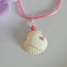 Sea scallop shell wire-wrapped pendant necklace. Adorned with pink rhinestone and on a pink cotton cord. Handmade Pink Shell-shaped Jewelry, Handmade Pink Shell Jewelry, Adjustable Pink Shell Jewelry, Pink Adjustable Shell Jewelry, Pink Adjustable Shell Necklace As Gift, Handmade Pink Shell Necklace, Handmade Pink Shell As A Gift, Handmade Pink Shell, Handmade Pink Shell As Gift