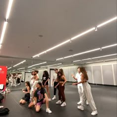 a group of people standing around each other in a room with lights on the ceiling