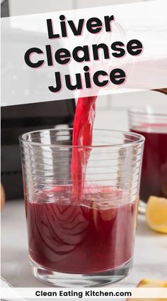 a person pouring liquid into a glass filled with juice on top of a counter next to sliced lemons