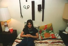 a woman sitting on her bed looking at her phone