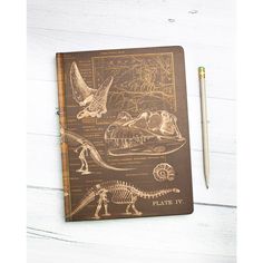 a notebook with dinosaurs on it next to a pencil and some other things in front of it