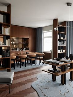 a living room filled with furniture and a dining table surrounded by bookshelves in front of a window