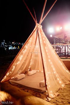 a bed with lights on it in the middle of a beach area at night time