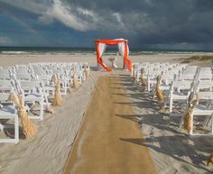 an empty beach with rows of white chairs set up for a wedding on the sand