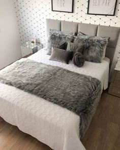 a bed with pillows and blankets on top of it in a room that has wood floors