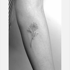 a woman's leg with a single flower tattoo on the left side of her arm