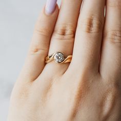 a woman's hand with a yellow gold ring on it and a diamond in the middle