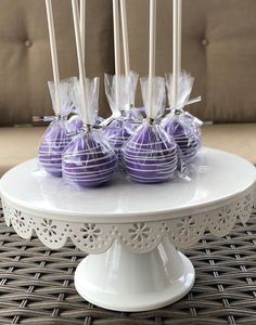 purple cake pops are sitting on a white platter