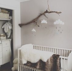 a white crib in a baby's room with a tree branch hanging from the ceiling