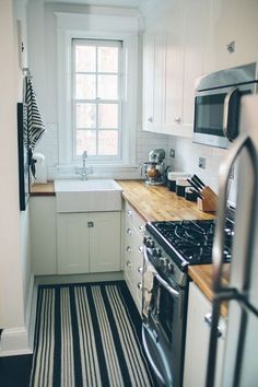 a kitchen with black and white striped flooring next to a stove top oven under a window