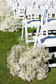 rows of white chairs with flowers in the grass