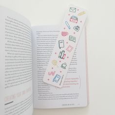 the bookmark is laying on top of an open book, which has stickers in it