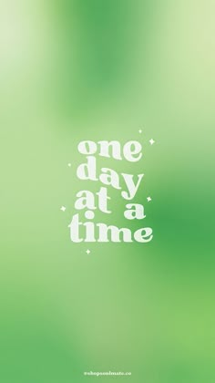 the words one day at a time are written in white on a green blurred background