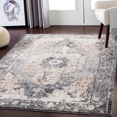 a large area rug with an ornate design in grey, beige and pink colors on a hardwood floor