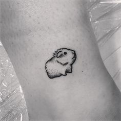 a black and white photo of a small hamster tattoo on the left side of the leg