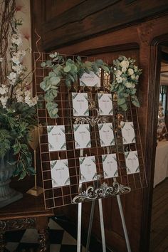 a wedding seating chart with flowers and greenery on it in front of a fireplace