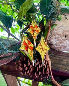 an ornament hanging from a tree branch with pine cones and leaves around it