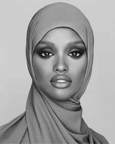 a woman wearing a headscarf and makeup looks into the camera with an intense look on her face