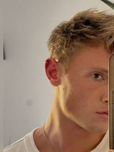 a young man holding up a mirror to his face