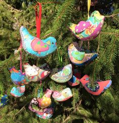 colorful ornaments are hanging from the branches of a christmas tree, decorated with birds and flowers