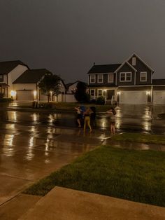 three children playing in the rain at night