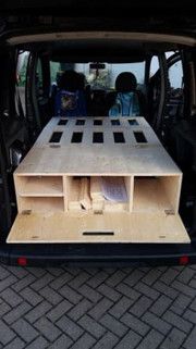 the back end of a van with an open hatchback and wooden shelves in it