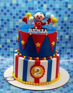 a birthday cake with a clown on top and balloons in the shape of number two