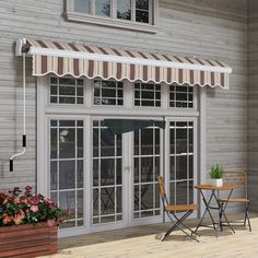 an awning on the side of a building with two chairs and a table in front of it