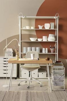 a white desk sitting in front of a shelf filled with cups and bowls on top of it