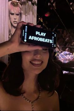 a woman holding up an electronic device with the words play afrobeats on it