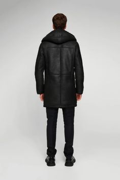 Men's Hooded Shearling Leather Coat In Black Wrap yourself in the luxurious warmth of this men's hooded shearling leather coat in sophisticated black. Expertly crafted from genuine sheepskin leather with a semi-aniline finish, this coat features a plush faux shearling inner shell. The stylish button closure, hooded collar, and open hem cuffs with shearling detail combine functionality with fashion. With two side pockets for convenience, this coat is the epitome of winter elegance and comfort. Ou Mens Shearling Coat, Leather Shorts Women, Short Leather Skirts, Leather Jumpsuit, Shearling Vest, Distressed Jacket, Studded Jacket, Sheepskin Jacket, Western Jacket