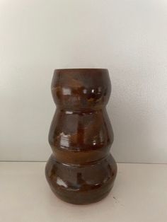 a brown vase sitting on top of a white table