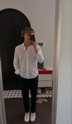 a man taking a selfie in front of a mirror wearing white shoes and black pants