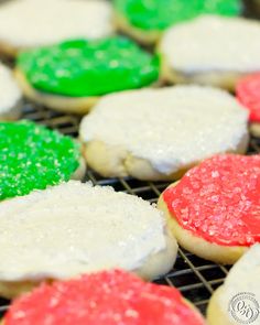 some cookies with different colored frosting and sprinkles are on a cooling rack