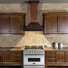 a stove top oven sitting inside of a kitchen next to wooden cupboards and counter tops