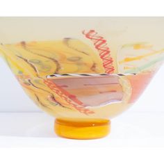 a yellow glass bowl sitting on top of a white table next to a wooden base