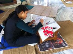 a woman sitting on the floor working on her laptop