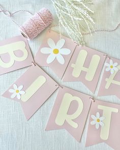 pink and white banner with flowers on it that says happy birthday hanging from the string