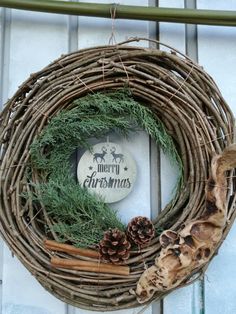 a christmas wreath hanging on the side of a building with pine cones and cinnamon sticks