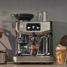 an espresso machine sitting on top of a counter next to a cup of coffee