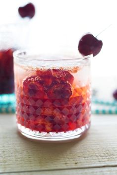 a small glass filled with liquid and cherries